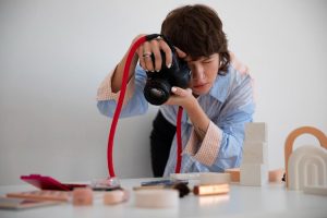 A person carefully photographing small objects on a table using a DSLR camera during short term courses in photography