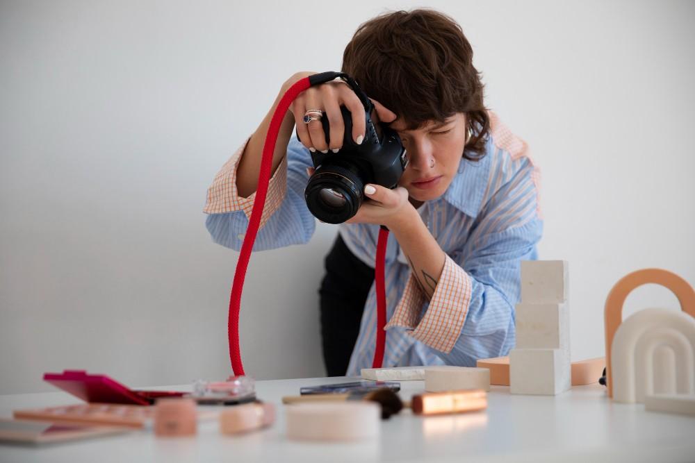 A person carefully photographing small objects on a table using a DSLR camera during short term courses in photography